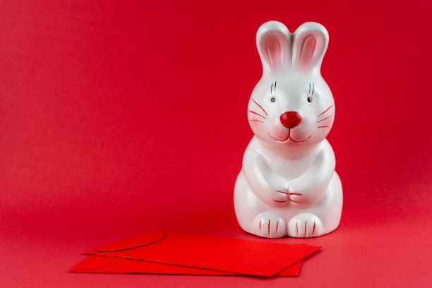 兔子硬币银行，红色背景的红包兔年概念图片下载