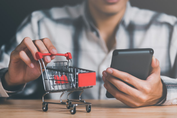 男人的手抓购物车，消费社会，购物狂概念，网上购物服务，并提供送货上门，连接世界各地的商家和客户，在线支付图片下载