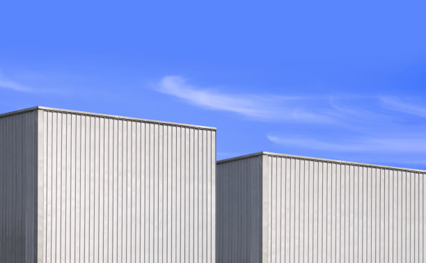 蓝色天空背景下的两座波纹金属工业仓库图片下载