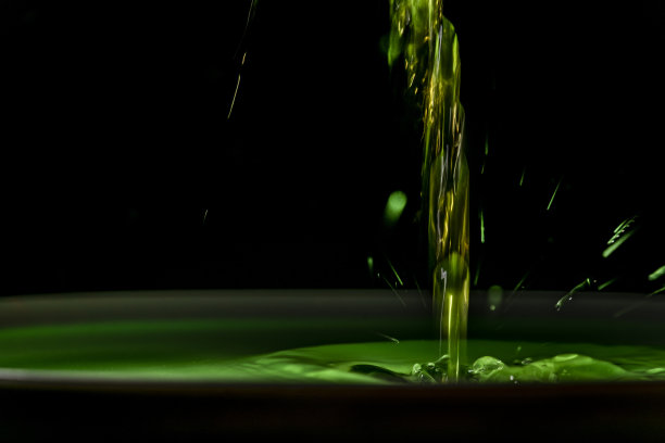 绿色鲜奶滴入绿色牛奶杯中，杯底深色图片下载