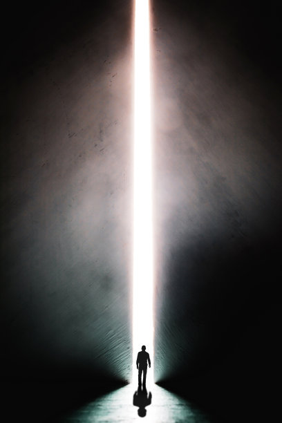 一个男人的剪影走向一盏明亮的灯在开放的巨大的墙壁。隧道尽头的一束光。成功的概念，选择的自由，开放的思想，冥想。图片下载