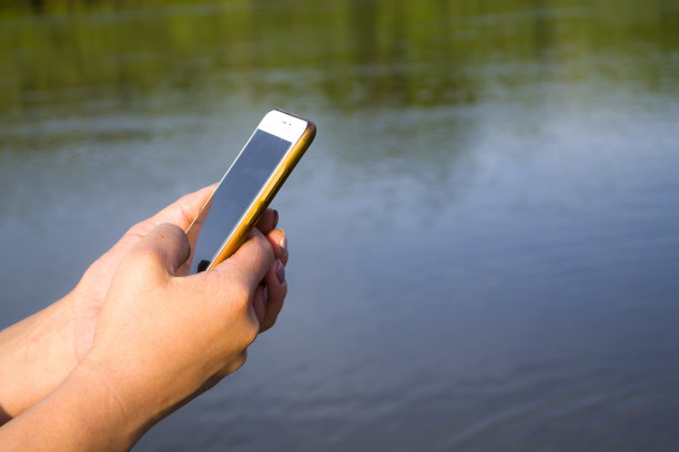 手持手机与空白屏幕显示移动应用程序对海滩户外。剪裁,模型图片下载