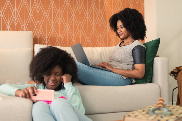 妈妈用笔记本电脑工作，女儿用手机图片下载