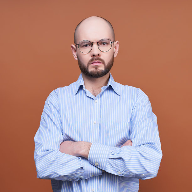 一个冷静、自信的商人，戴着眼镜，双臂交叉放在胸前。图片下载