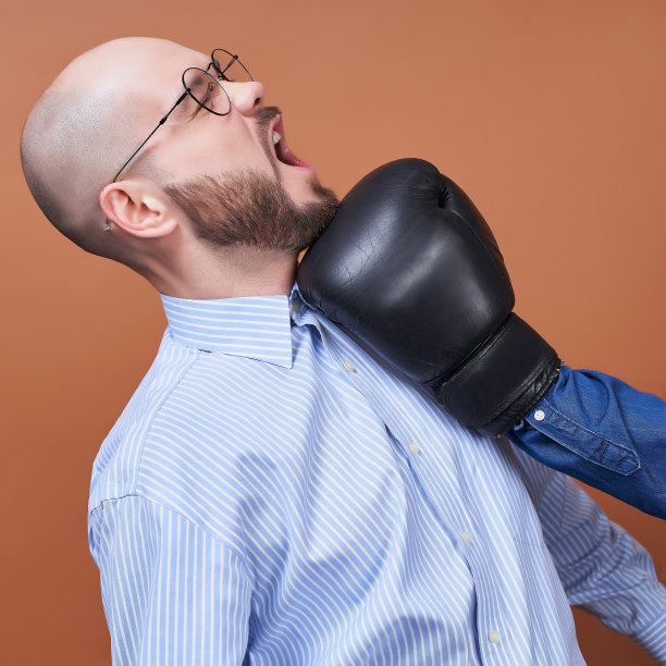 一张个人资料照片，一个戴着圆形眼镜和衬衫的男人被一只拳击手套击中了脸。图片下载