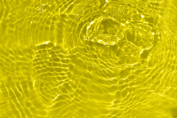 离焦模糊透明金色清晰平静的水面纹理与飞溅和气泡。潮流抽象的自然背景。水波在阳光下带有焦散。黄水闪烁图片下载