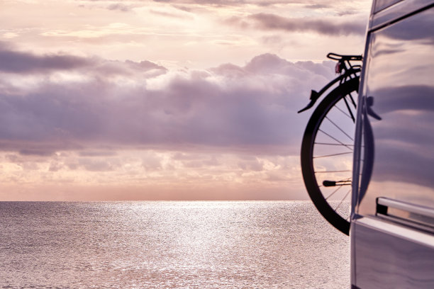 日落时的海景，露营车的后部，前面有自行车图片下载