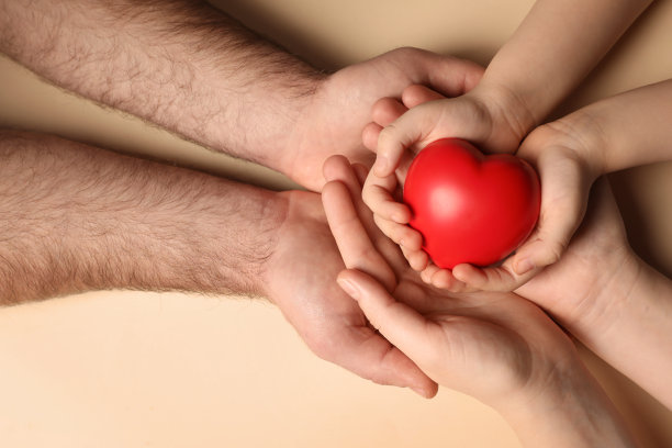 在米色背景上，俯视图，父母和孩子手里拿着红色的心图片下载