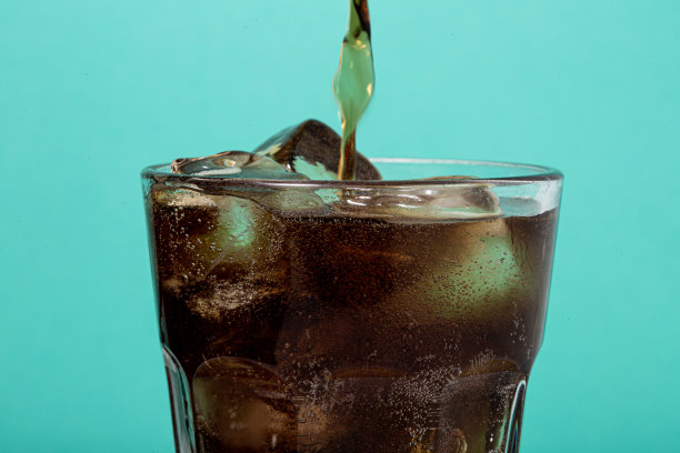 蓝色背景的杯子。一杯可乐加冰。图片下载