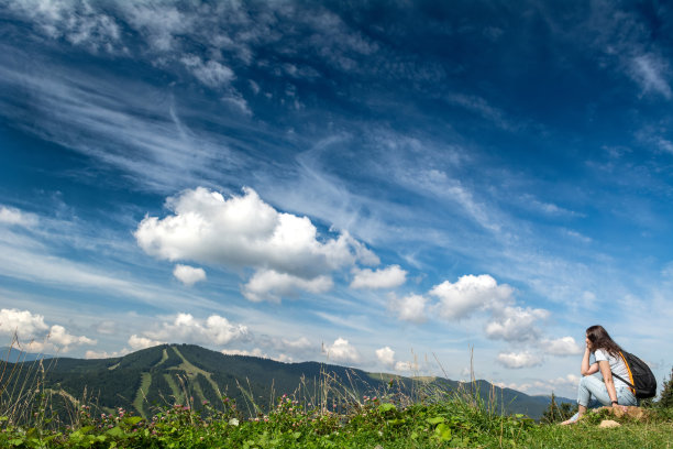 体贴的女孩在山的背景。一个背着背包的游客。美丽的喀尔巴阡风景与云。图片下载