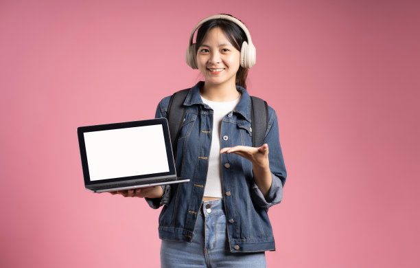 图片的亚洲学生女孩拿着笔记本电脑和孤立的粉红色背景图片下载