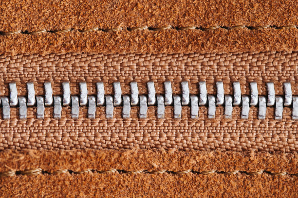 金属拉链。棕色麂皮织物。纺织品的背景。图片下载