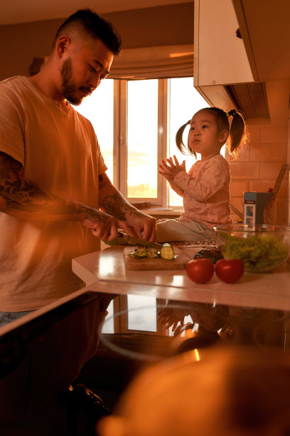 女孩看着爸爸切黄瓜做沙拉图片下载