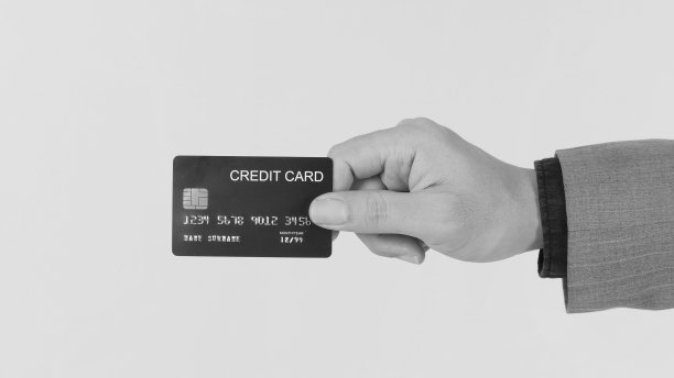 有一只手拿着黑色信用卡，穿着白色背景的西装。图片下载