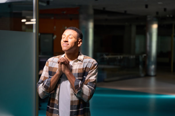 年轻英俊的男人在办公室祈祷图片下载