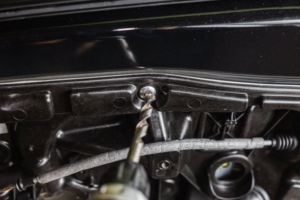 一个汽车修理工正在修理车门。一个汽车修理工从车门上钻出一个汽车铆钉。用钻头和钻头工作。图片下载