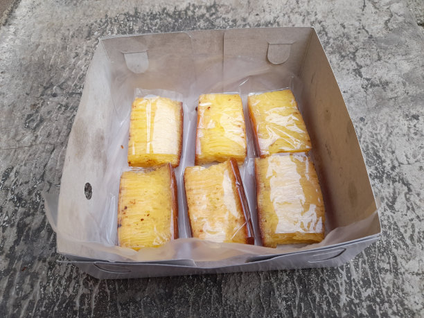 以街道为背景的纸盒里的Bika安香蛋糕。烹饪背景概念，小吃，餐厅，食谱，食品商业，包装，包装，生活方式图片下载