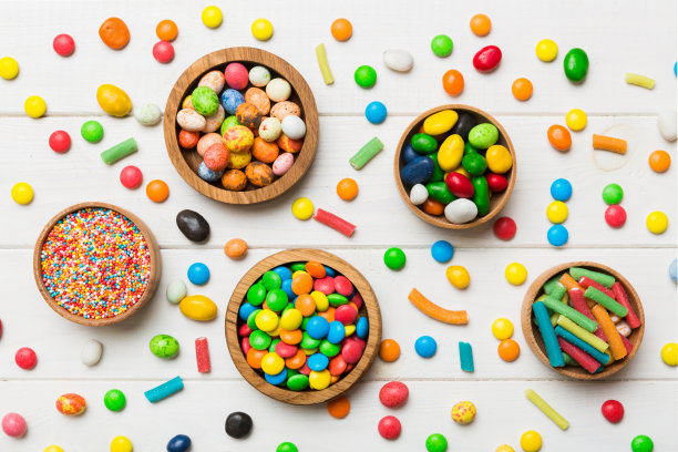 不同颜色的圆形糖果在碗和罐子。顶部视图的大品种糖果和糖果与复制空间图片下载