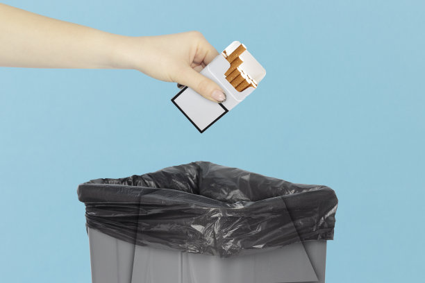 扔一包香烟在垃圾桶里，手里拿着香烟在垃圾桶前，戒烟，戒掉尼古丁图片下载