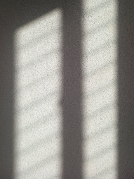 白色阴影的背景从窗户上的白墙。摘要粗糙的墙壁上的光影。背景上的阴影。图片下载