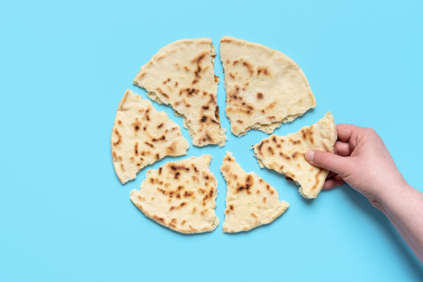 上图是印度扁面包。女人拿着一块馕饼图片下载