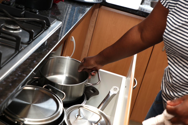 一个在厨房工作的家政工人在洗碗，把锅放在抽屉里图片下载