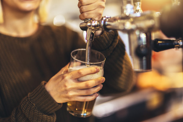 女调酒师在酒吧敲啤酒。图片下载