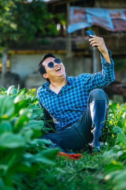 亚洲农民在田里用智能手机说话的肖像。农业商业、技术、传播和生活方式概念。图片下载