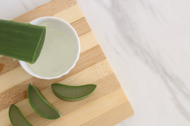 芦荟片和一碗芦荟胶放在砧板上。图片下载