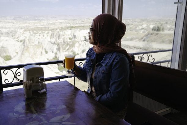 亚洲穆斯林妇女坐在咖啡馆里，看着格瑞姆公园图片下载