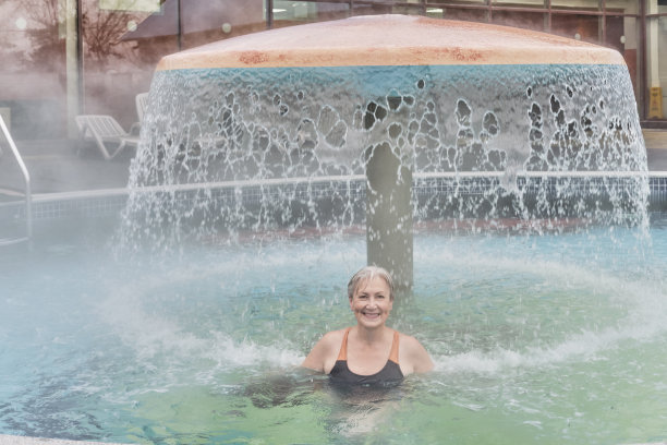 快乐微笑的高级妇女与短灰色的头发下喷射淋浴，装饰蘑菇水图片下载