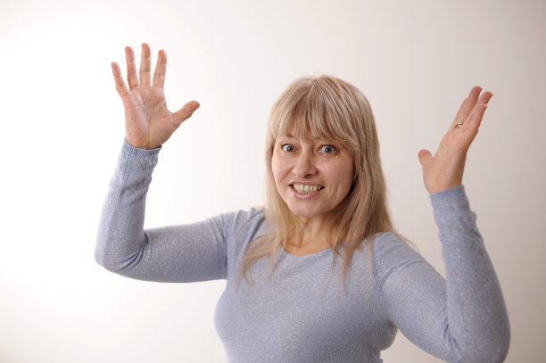 快乐快乐的成人美丽的女孩举起你的手看着相机微笑着笑在白色的背景女人短发和不化妆干净的面部皮肤微笑着，站着图片下载