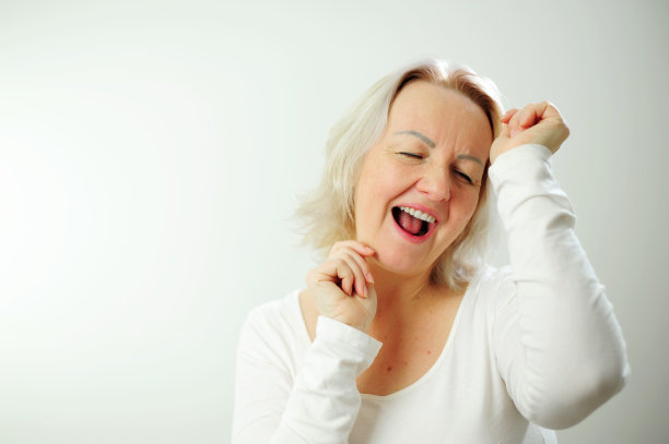 一个成年女子在跳舞，她张开嘴，举起手臂，微笑着，许多积极的情绪赢得t恤背景和白发，为您提供邀请广告的聚会场所图片下载