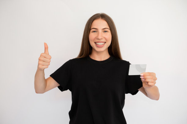 快乐的年轻女子的肖像与信用卡制作大拇指图片下载