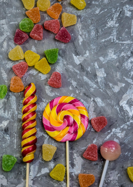 不同形状和颜色的糖果在灰色的木质背景上。软的焦点。一个复制的地方。灰色背景上的棒棒糖，有空间复制。背景，横幅关于一个背景与糖果。图片下载