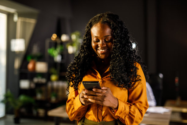 微笑的年轻女商人在办公时间回复短信图片下载