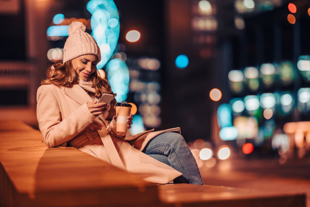 一个女人晚上在城里用手机图片下载