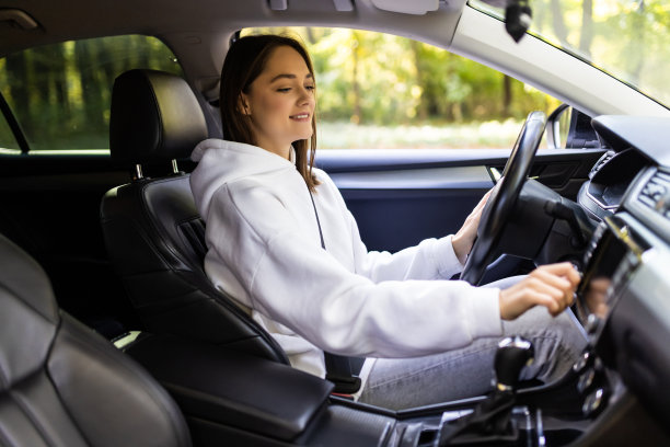 搜索最喜欢的音乐。年轻女子一边开车一边微笑着按按钮图片下载