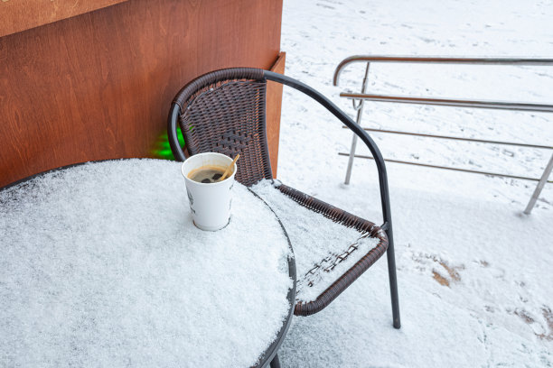 在雪地上用一次性纸杯盛咖啡。冬天空无一人的街头咖啡馆。图片下载