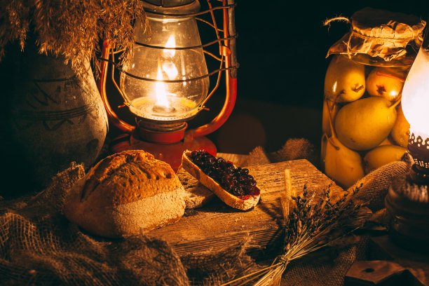 在蜡烛的照耀下，木桌上放着果酱面包。图片下载