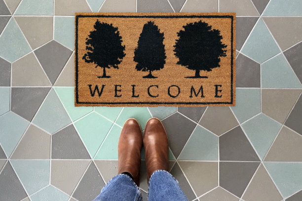 设计师欢迎进入门垫放置在彩色瓷砖地板与棕色鞋图片下载