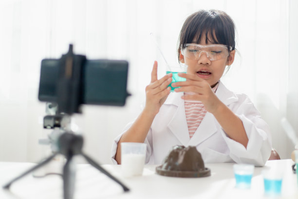 亚洲女学生做简单的化学实验并为他的追随者录制视频，年轻的博主孩子在镜头前为vlog摆姿势，儿童为社交媒体渠道概念制作vlog。图片下载
