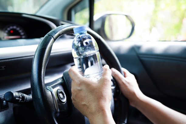 亚洲女司机在车里拿冷水喝，很危险，有发生事故的危险。图片下载