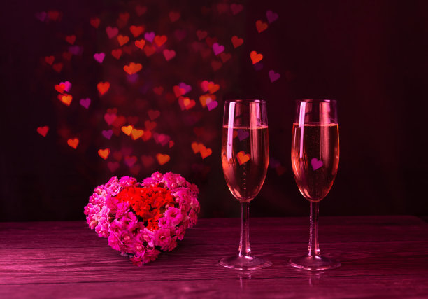 两杯粉色香槟和许多虚化的心。一大颗鲜花的心。情人节。情人节。图片下载