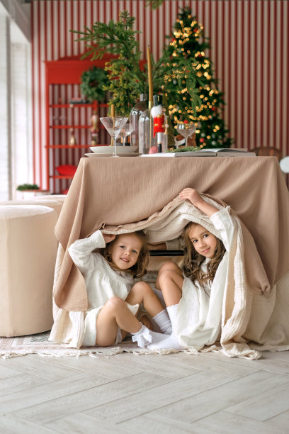 姐妹们在铺着桌布的喜庆桌子下玩捉迷藏。图片下载