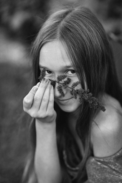 一个拿着花的女孩。大自然中的女孩。近似的照片。脸边的花图片下载