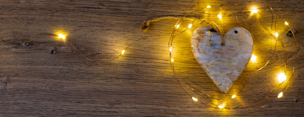 旗帜或白桦木的心脏被一串黄色的灯照亮在一个木制背景图片下载