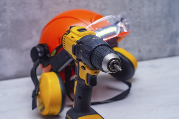 电动螺丝刀和一顶建筑安全帽，头上有听筒，桌上有头灯。保护用施工工具和形式。图片下载