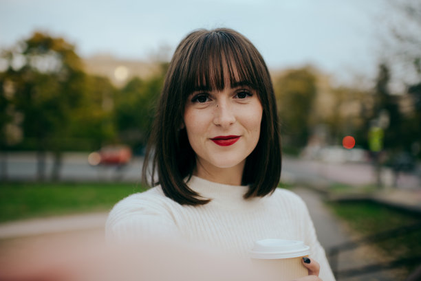 秋天的布达佩斯，一名年轻女子在街上用智能手机自拍图片下载