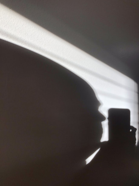 墙上的影子。一个男人的头看着电话。图片下载